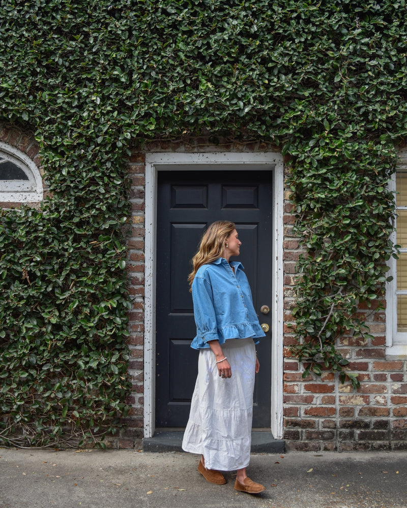 Woman standing in a doorway with ivy-covered walls