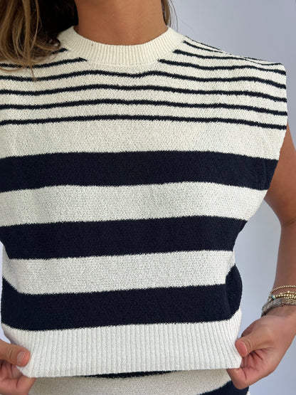 Close-up of a person's shoulder wearing a sleeveless top with navy and white horizontal stripes.