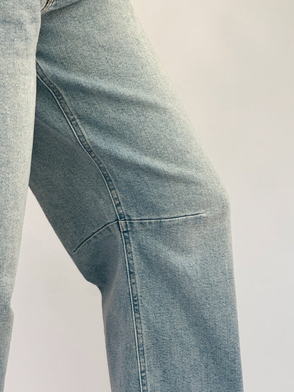 Close-up of a person wearing light blue denim jeans with visible stitching and texture, against a neutral background, conveying a casual tone.