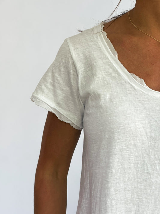 A close-up of a person wearing a white, distressed t-shirt with a frayed neckline. The background is plain white, creating a minimalistic feel.
