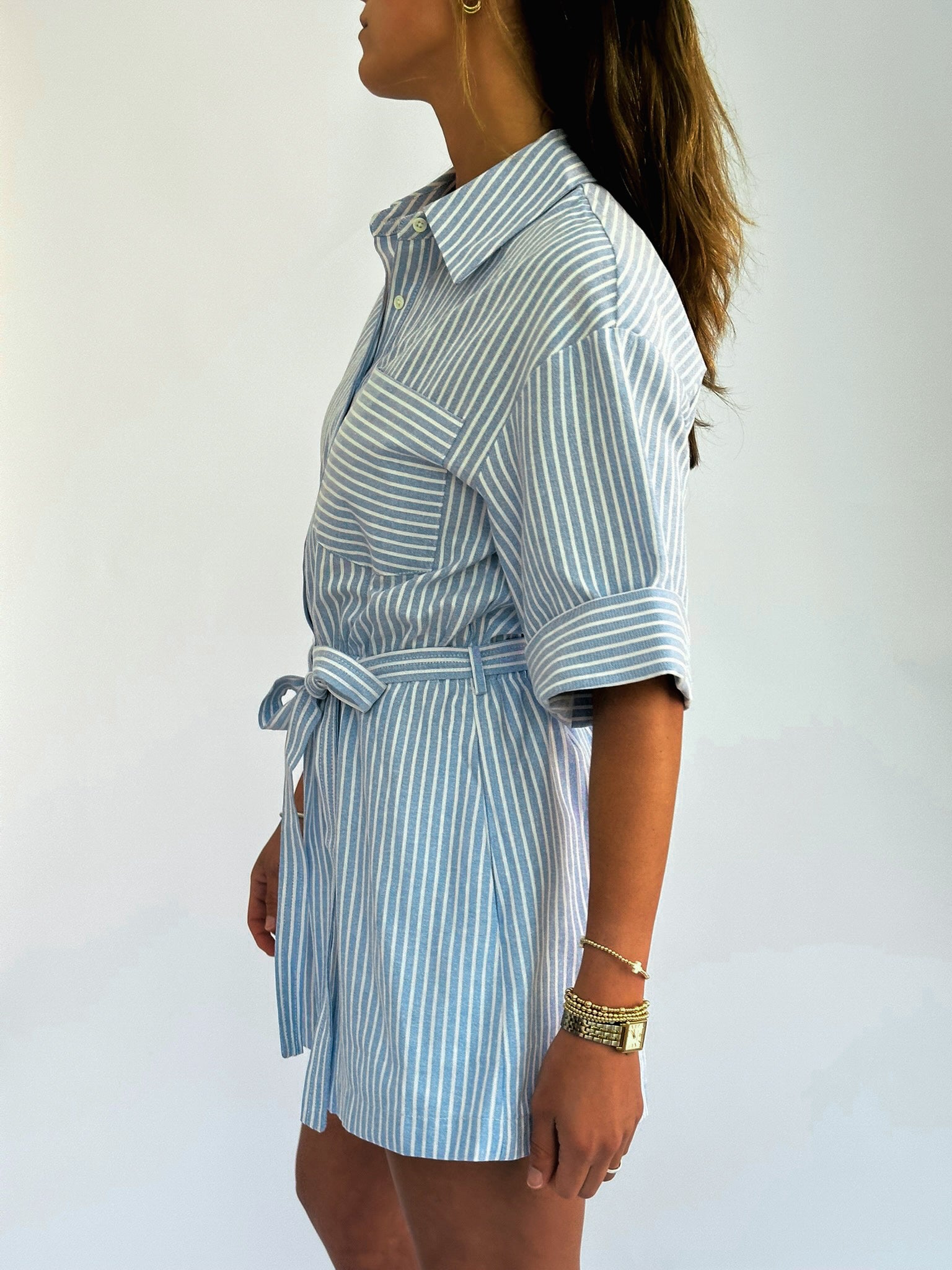 Woman wearing a blue and white striped romper against a white background