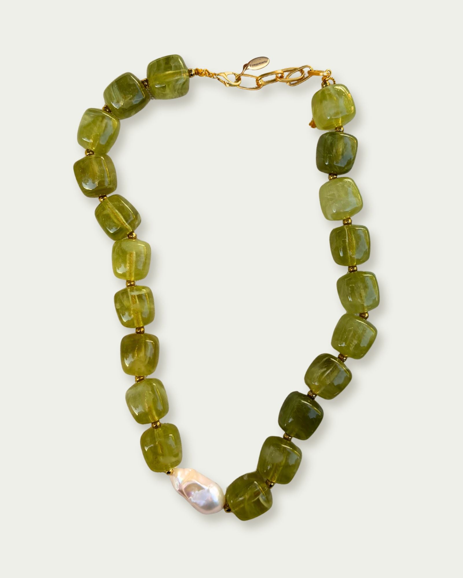 Necklace made of square, green jade beads with a central white pearl. Features a gold clasp. The design is elegant and earthy.